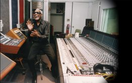 Ray Charles in studio engineering room next to sound equipment and mixer