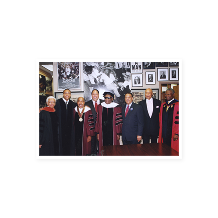 Ray Charles in a cap and gown with representatives from Morehouse College