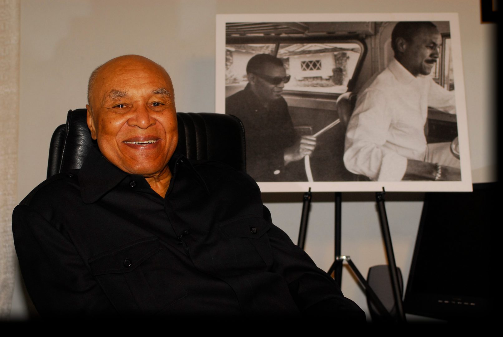 Joe Adams sitting in front of photo of Ray Charles